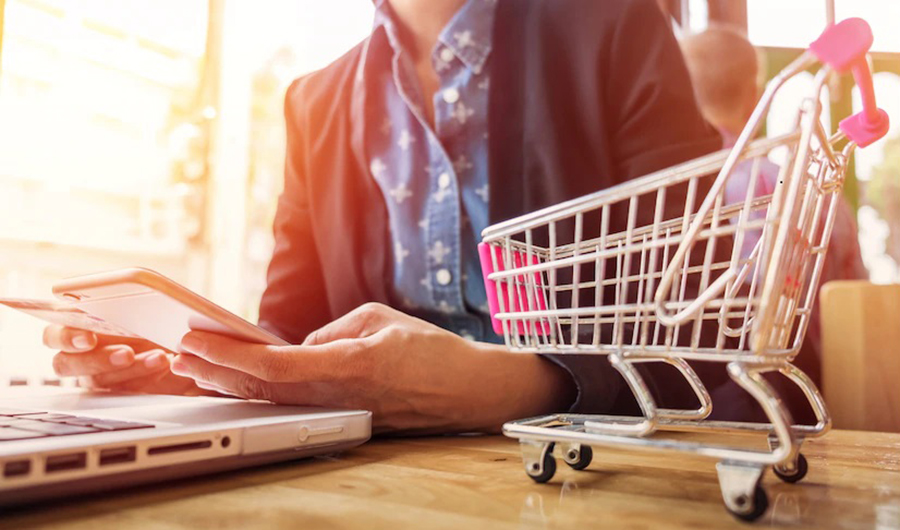 Woman inputting card information key phone laptop while shopping online